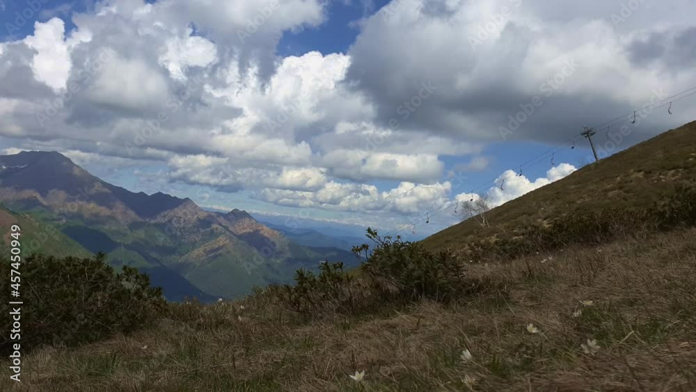 Time-lapse of running clouds and mountain range of Italian Alps with chairlift. Zoom out
