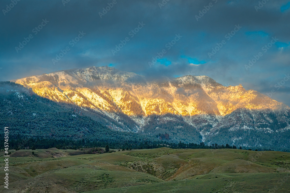 2021-06-01 A ABSAROKA MOUNTAIN RANGE WITH LOW CLOUDS AND SUN BREAKING THROUGH IN MONTANA