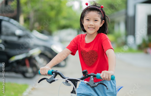 a girl ride a bicycle, kid happy and smile, asian child