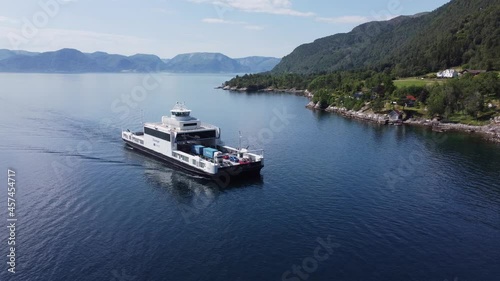 Car and passenger ferry Mf Stavanger from company Norled transporting cars over the Sognefjord at E39 road between Oppedal and Lavik - Backwards moving sunny day aerial with ferry in center of frame photo