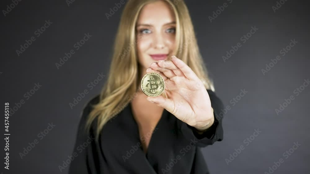 Blonde smiling woman holding coins,showing a bitcoin coin to camera. Blonde smiling woman holding coins,showing a bitcoin coin to camera.