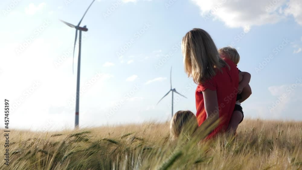 Mother with Young Kids in Summer Field with Blurred Wind Turbine SLOMO Mother with Young Kids in Summer Field with Blurred Wind Turbine SLOMO