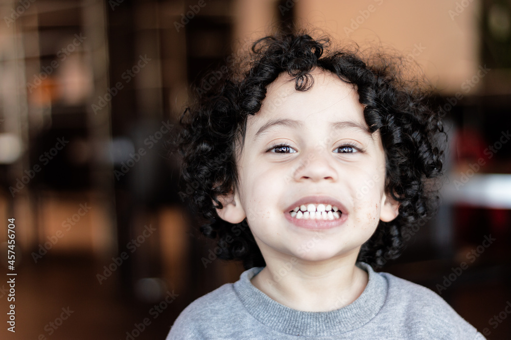 close-up portrait of a smiling white latin minor boy with black curls, inside a fast food establishment. close-up portrait of a smiling white latin minor boy with black curls, inside a fast food establishment.