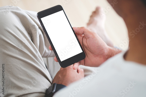 Close up view casual man sitting in living room and using smart phone.