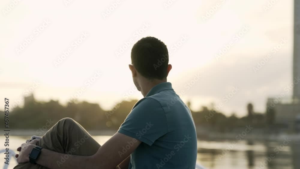 Orbiting shot of man peacefully sitting on bow of boat watching sunset Orbiting shot of man peacefully sitting on bow of boat watching sunset