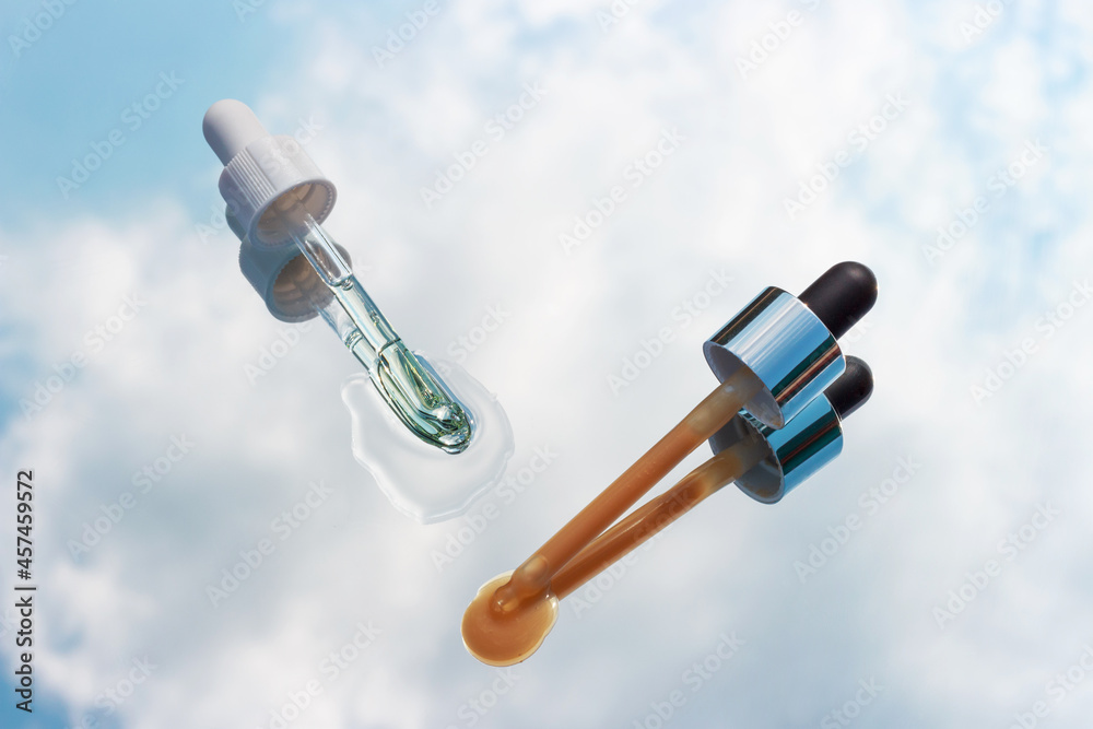 Pipettes with oil and serum on mirror reflected in blue sky. Pipettes with oil and serum on mirror reflected in blue sky.