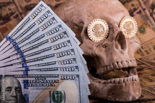 Decorative gilded medallion with pseudo-precious stones and the symbol of the American dollar in the eye sockets of a dummy human skull 