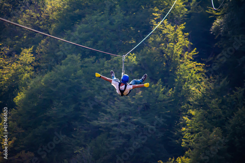 Fun, adrenaline and adventure on the zip line.  Teenager having fun on a zipline on panoramic forest background. Zipline in the forest. People get adrenaline through the zipline in the forest