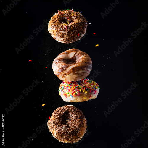 Sweet appetizing donuts on a black background. Levitation. Minimalism. There are no people in the photo. Sweet food, Birthday, holiday, delicious food, calories.