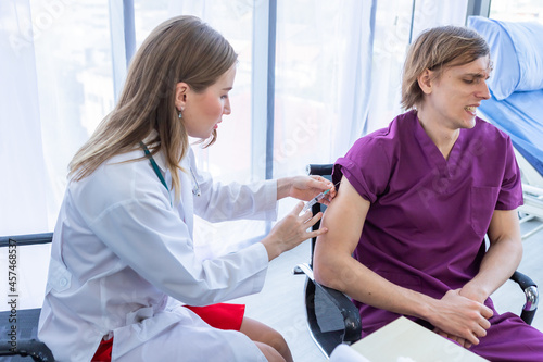 Close-up of female doctor with syringe to the arm of a man patient  on Bed for better healing In the room hospital background.