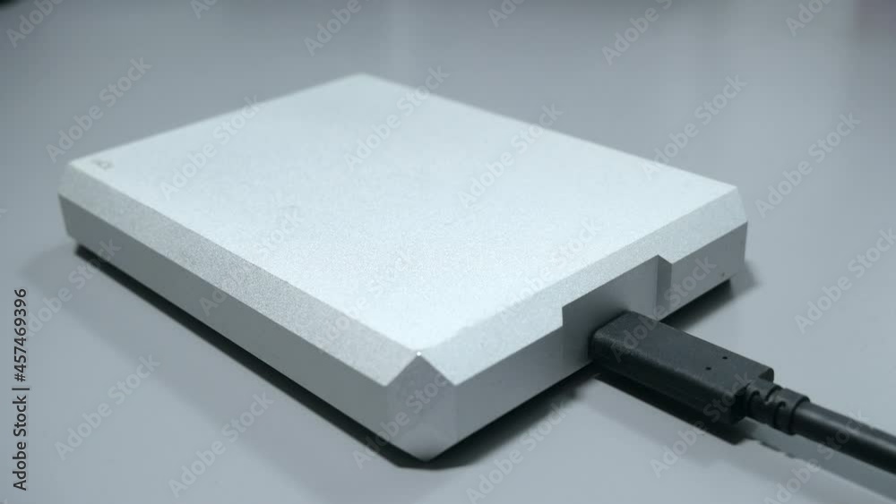 Hand connecting USB C cable into portable hard drive storage device