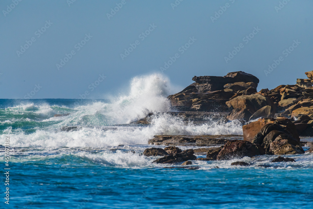 Clear blue skies, splashes on the rocks at the seaside