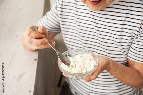 An elderly woman eats cottage cheese for breakfast.