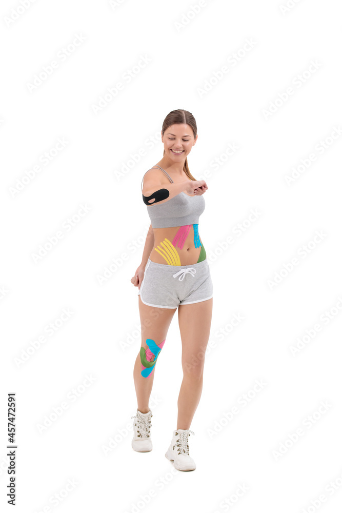 Physio tapes applied to the body of happy young athletic woman isolated on white. Physiotherapy, kinesio taping, kinesiology and recovery treatment concepts. Physio tapes applied to the body of happy young athletic woman isolated on white. Physiotherapy, kinesio taping, kinesiology and recovery treatment concepts.
