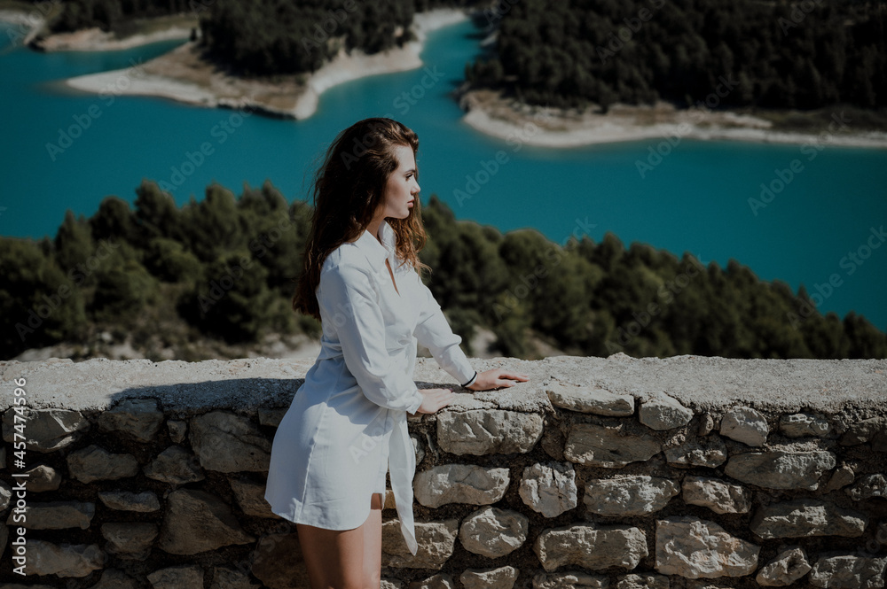 Fashion model posing in white mini dress on the top of the mountain.