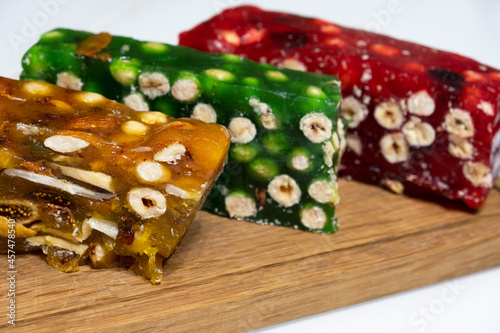 Turkish delight. Oriental orange, green and red candy marmalade. Eastern sweets with sugar and nuts. Lukum is on white background. Delicious food. Dessert for dreams. Lukum on wooden board. Isolated