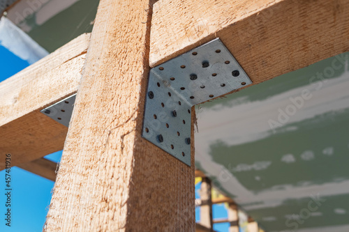 Construction of a timber frame house. Joining wooden beams using a galvanized metal corner and self-tapping screws.