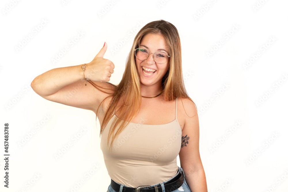 Happy woman with thumb up looking at camera. White background. 20 - 22 years old. White European woman. Happy woman with thumb up looking at camera. White background. 20 - 22 years old. White European woman.