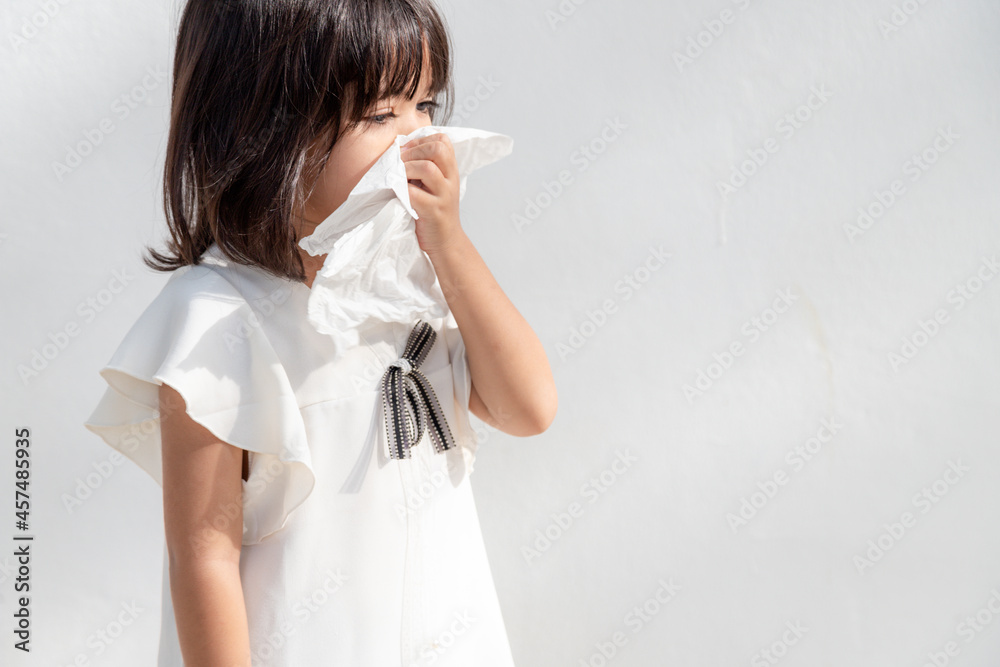 Asian child girl sick with sneezing on the nose and cold cough on tissue paper because weak or virus and bacteria from dust weather and kindergarten and preschool Asian child girl sick with sneezing on the nose and cold cough on tissue paper because weak or virus and bacteria from dust weather and kindergarten and preschool