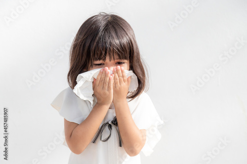 Asian child girl sick with sneezing on the nose and cold cough on tissue paper because weak or virus and bacteria from dust weather and kindergarten and preschool