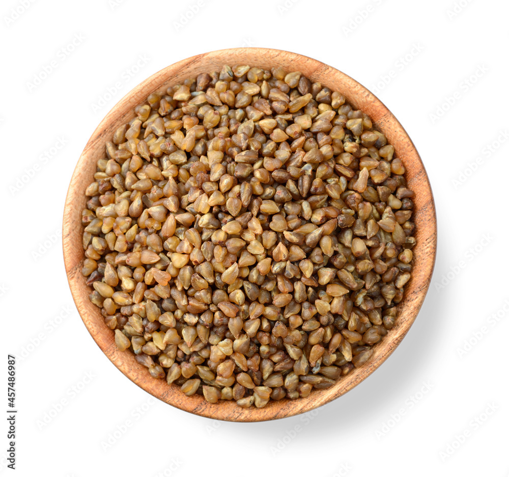 uncooked buckwheat in the wooden plate, isolated on the white background, top view