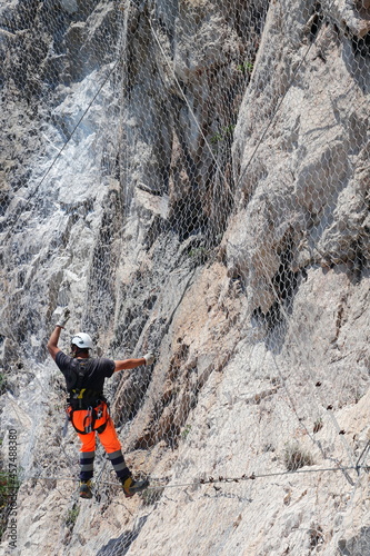 Man working on the installation of a rockfall protection mesh