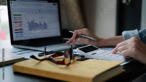 Close up hand woman doing finance and calculate with calculator on desk about cost , work from home concept