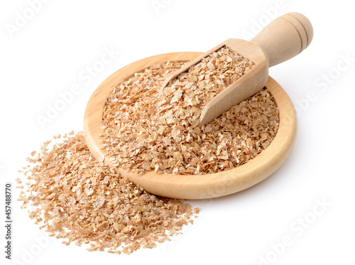 raw wheat bran in the wooden plate, with wooden scoop, isolated on the white background