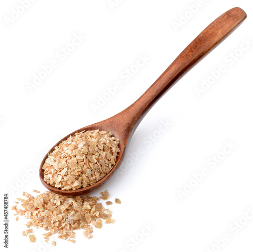 raw wheat bran in the wooden spoon, isolated on the white background