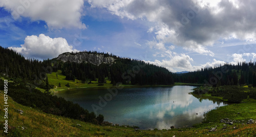 reflections in a mountain lake with hills and trees while hiking panorama