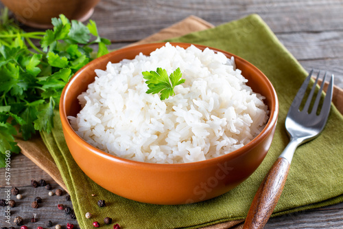 Cooked white rice garnished with parsley in a bowl (Selective Focus, Focus on the parsley and the rice around)