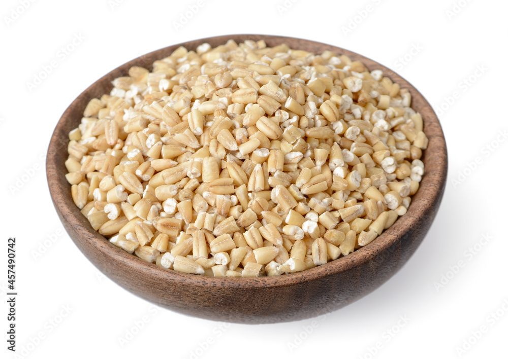 close up of raw steel cut oats in the wooden bowl, isolated on white. (large depth of field, taken with tilt shift lens)