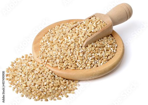 raw steel cut oats in the wooden scoop and plate, isolated on the white background