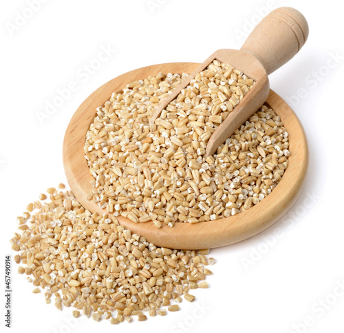 raw steel cut oats in the wooden scoop and plate, isolated on the white background