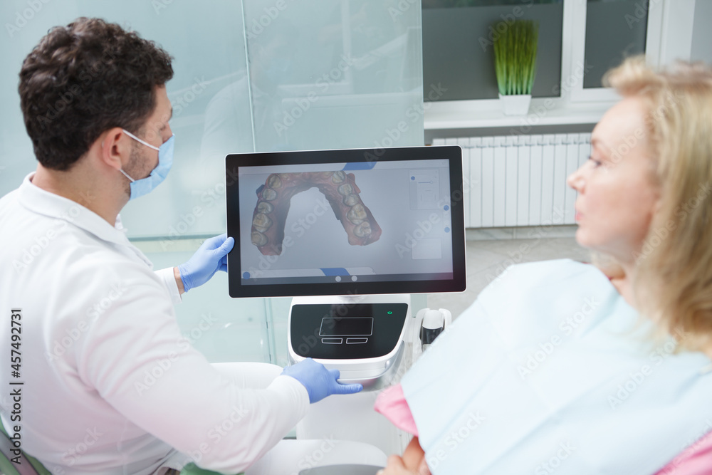 Dentist and patient looking at dental scan on the screen of computer Dentist and patient looking at dental scan on the screen of computer