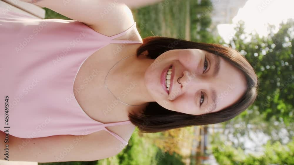 Vertical POV video call of young Asian woman talking to friends or colleagues while standing on city street.