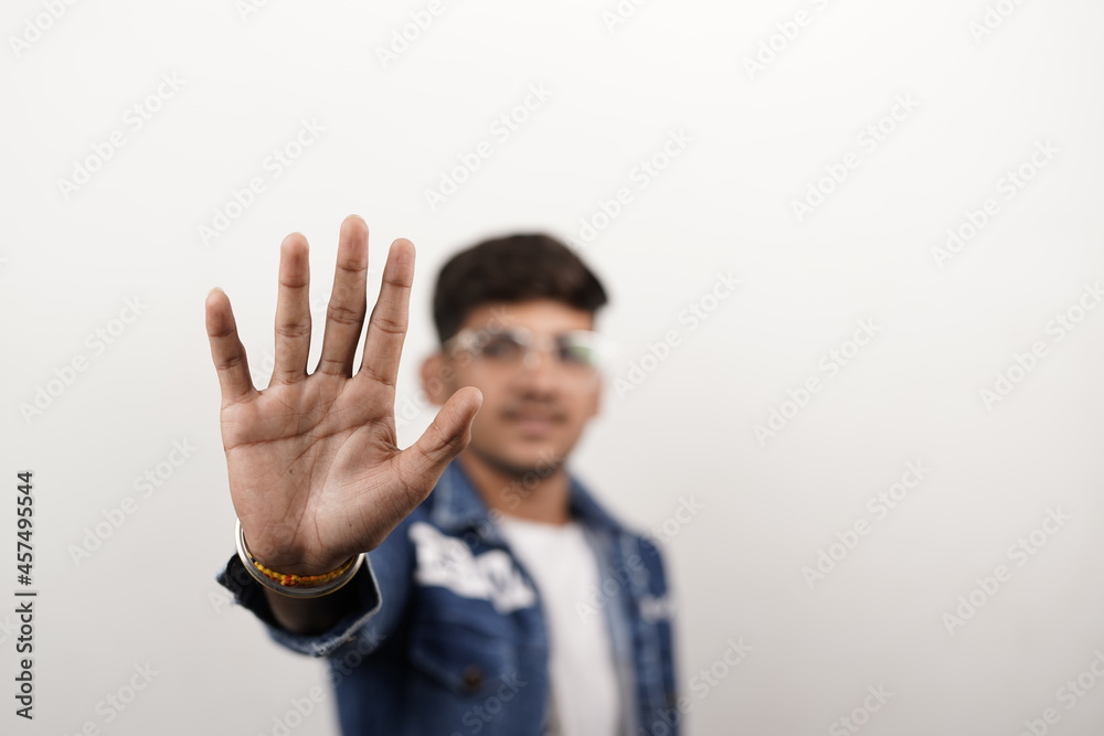 indian young man wearing casual clothes and glasses doing stop sing with palm of the hand. warning expression with negative and serious gesture on the face.K indian young man wearing casual clothes and glasses doing stop sing with palm of the hand. warning expression with negative and serious gesture on the face.K
