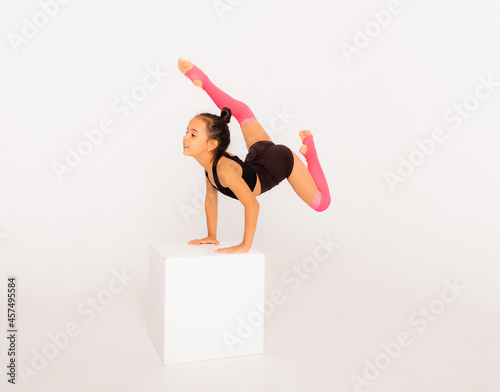 Obraz na plátně Little gymnast on a large white cube performs sports exercises