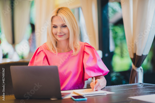 Photo portrait elder woman beautiful attractive with blonde hair working on laptop sitting in cafe
