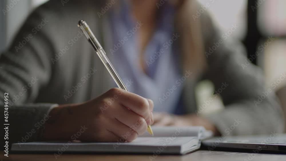 Close-up pen writes a lecture in a notebook notebook. Student writes with pen on paper