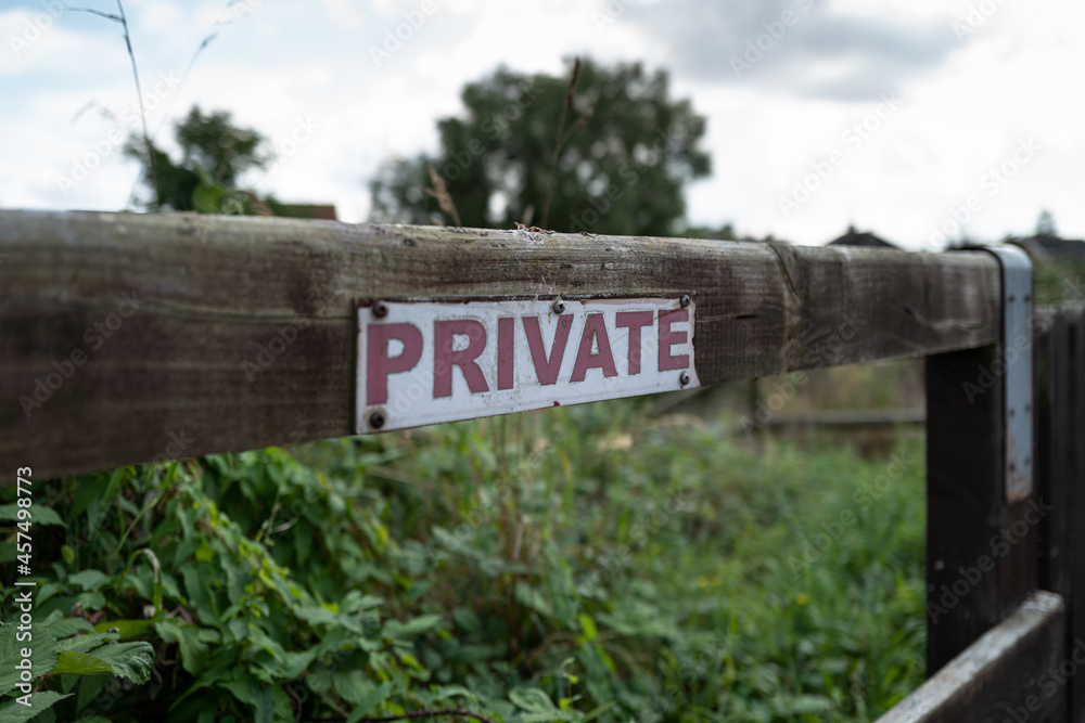 Shallow focus of a generic Private sign seen nailed to a wooden post at the edge of private gardens in London, UK.