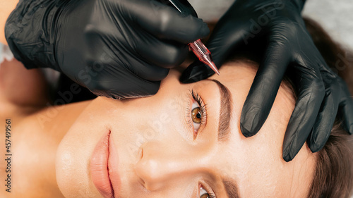 Bild auf Leinwand Make-up master performs the procedure of permanent eyebrow makeup