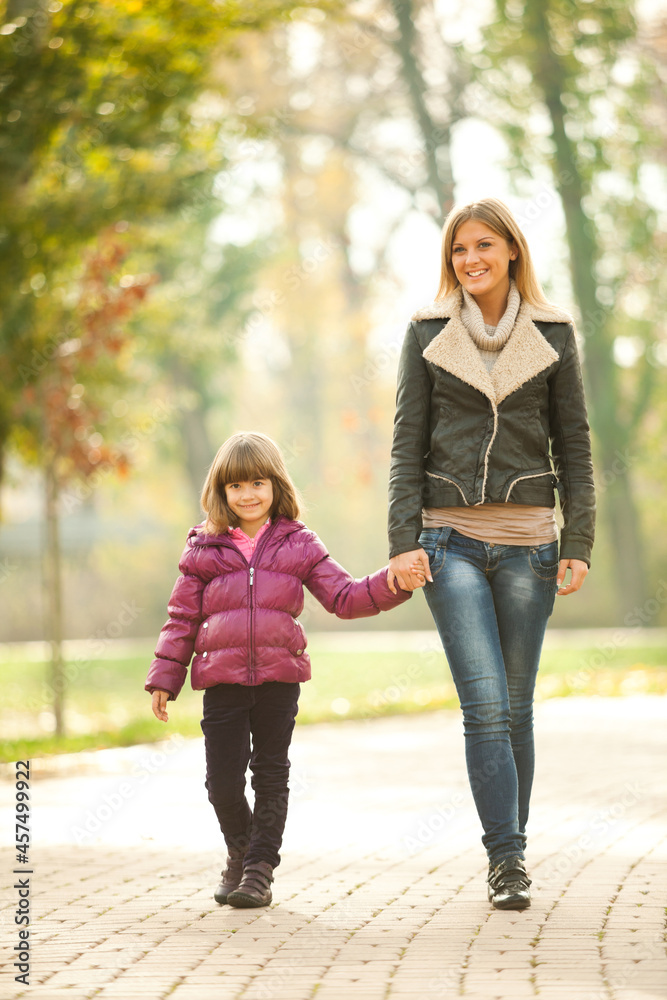 Obraz premium Mother and daughter walking in park in autumn.