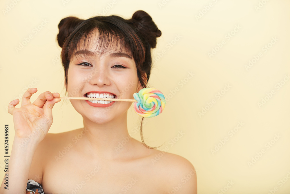 Funny beautiful young woman holding swirl lollipop on wooden stick in her mouth Funny beautiful young woman holding swirl lollipop on wooden stick in her mouth