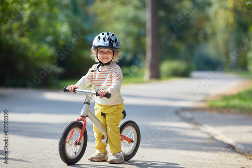 Fototapeta Naklejka Na Ścianę i Meble -  satisfied child on a balance bike in a helmet. On a sunny summer day.