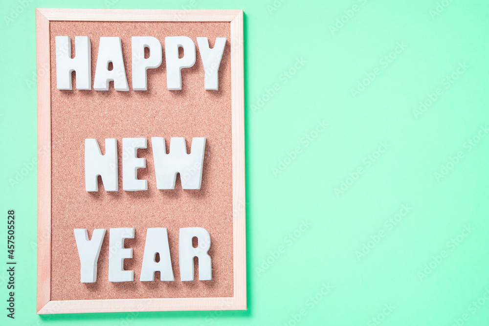 Inscription with plaster letters happy new year on a corkboard on a green background top view with place for text Inscription with plaster letters happy new year on a corkboard on a green background top view with place for text
