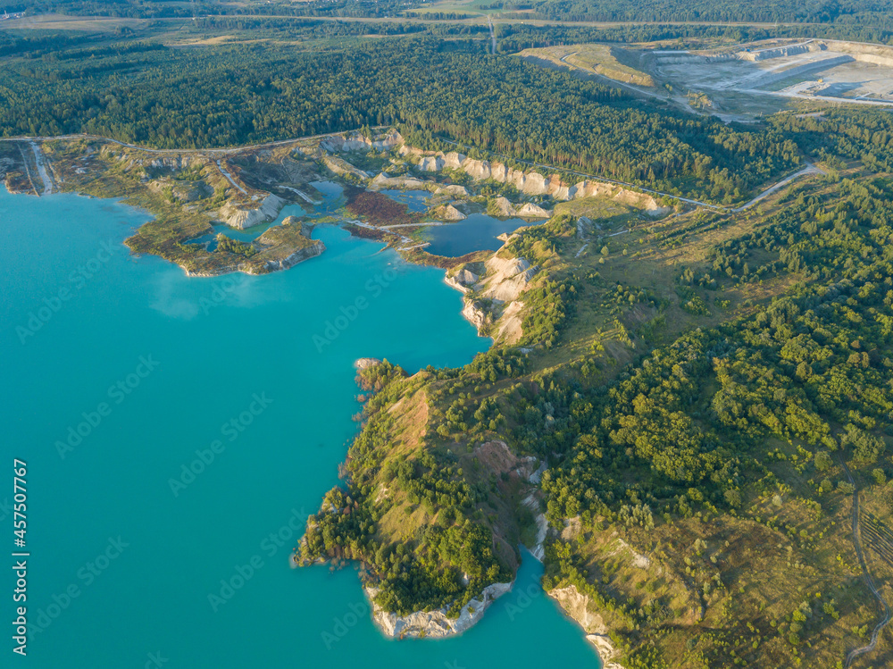 Drone view of an artificial lake of chalk quarries in Belarus near Krichev. Turquoise water in the summer season in an open pit. Man-made mountains formed during the extraction of chalk