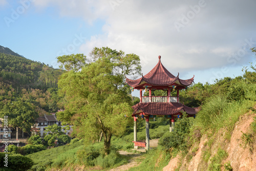 The green plants and red pavilions in the park are against the background of blue sky and white clouds