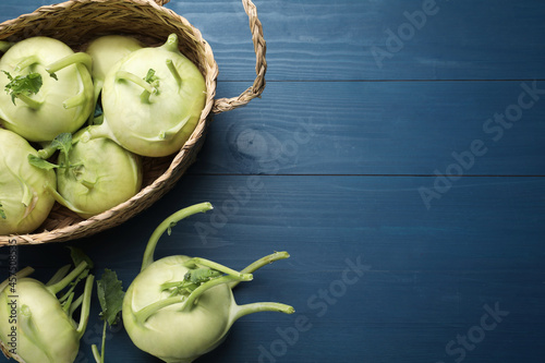 Whole kohlrabi plants on blue wooden table, flat lay. Space for text photo