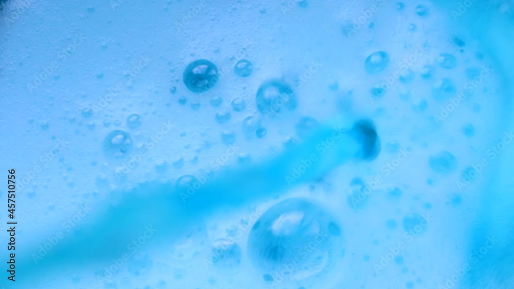 Blue sparkling beverage is poured into the glass pot with audio. Blue knitted background Blue sparkling beverage is poured into the glass pot with audio. Blue knitted background